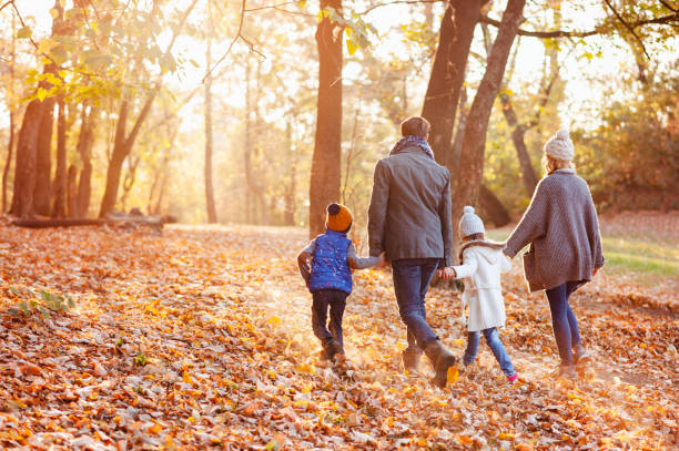 Happy family walking on the beautiful autumn day in the leafy autumn scenery.